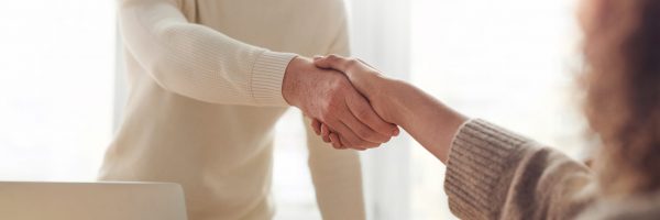 Realtor and client shaking hands after signing home purchasing agreement.